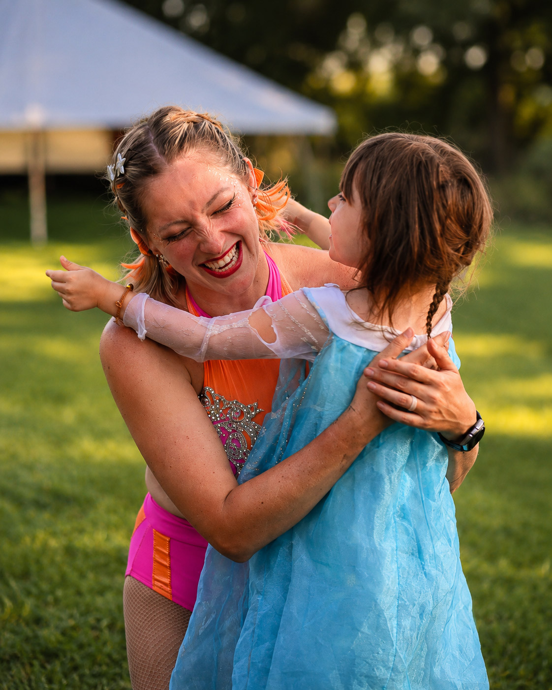 A performer sharing a hug with a young festival guest in costume
