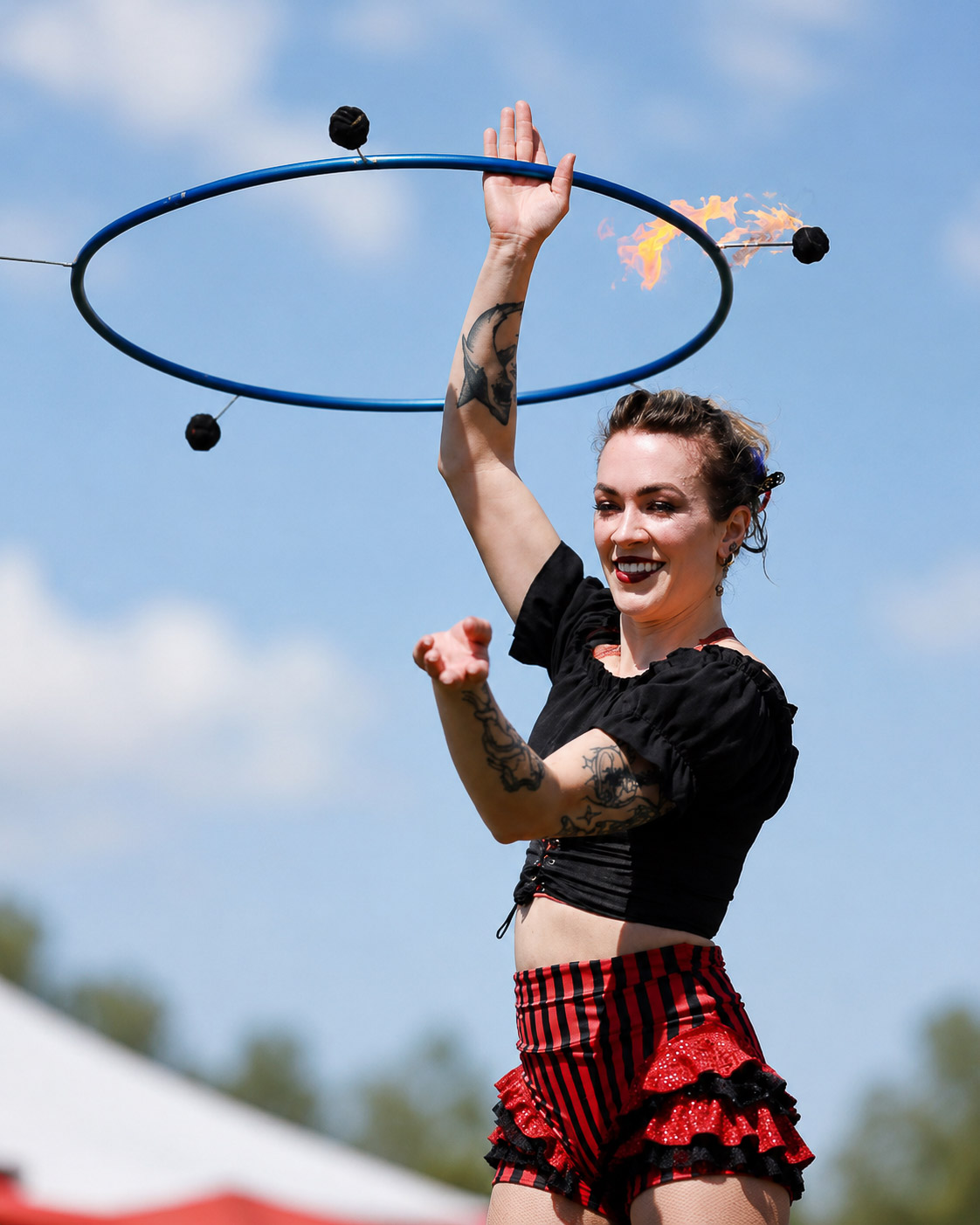 Fire hoop performer under a bright blue daytime sky